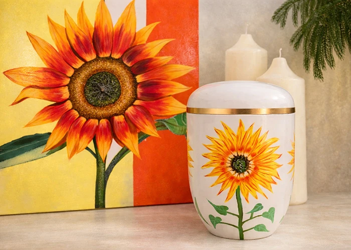 Handbemalte Sonnenblumen-Urne vor Sonnenblumengemälde mit Kerzen – Remuna Bestattungen Halle (Saale)