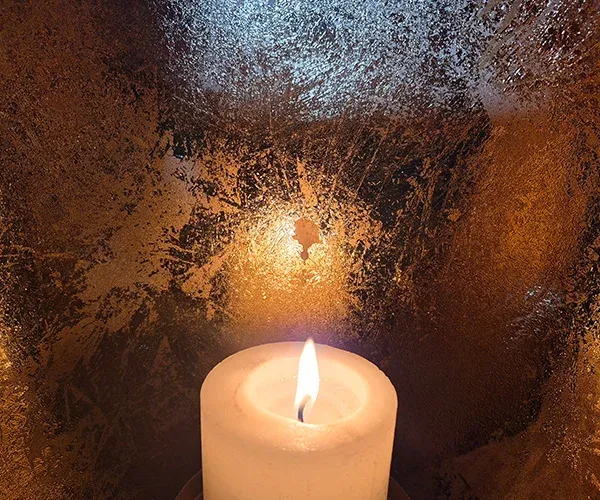 Brennende Kerze vor goldenem Hintergrund – Remuna Bestattungen Halle (Saale)